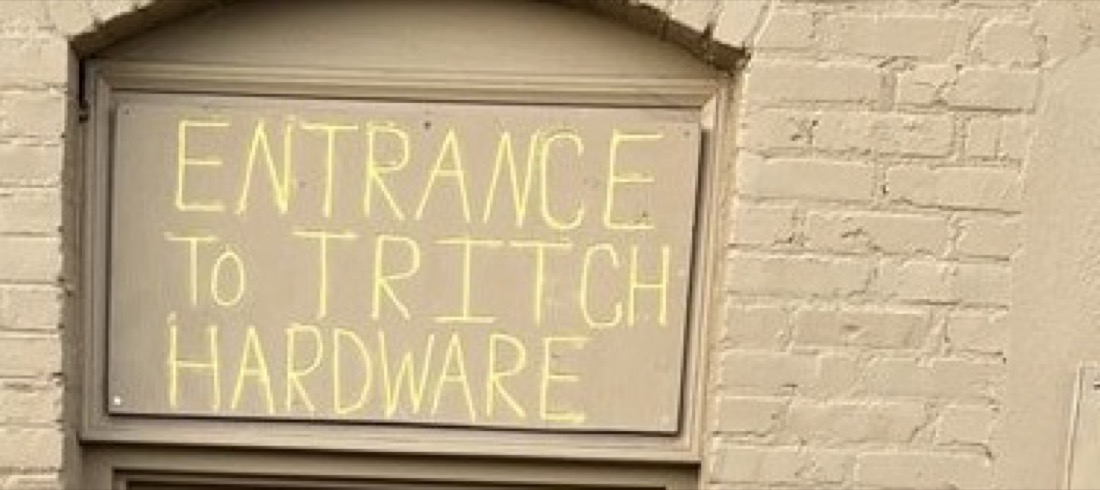 Our name hand-painted in yellow above the entrance: Entrance to Tritch Hardware.